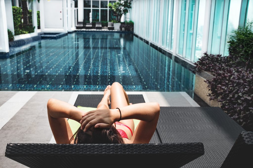 Femme qui bronze sur un transat, au bord d'une piscine