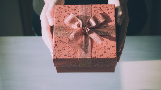 Jeune femme qui tient un cadeau contenant une médaille dans ses mains